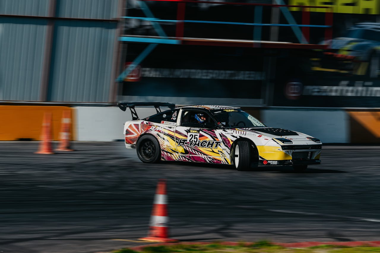 menu-09 Race car expertly drifting around cones on a track during a race event. Vibrant colors and motion blur enhance action.
