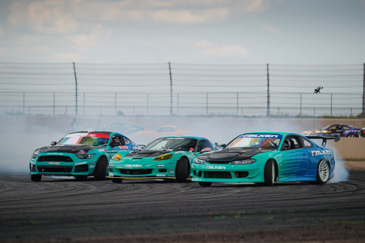 menu-11 Exciting drift action featuring cars with Falken Tyres livery at a racing circuit.